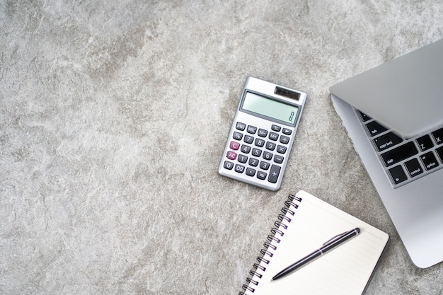 Workspace with calculator, pen, laptop on the rock stone background.