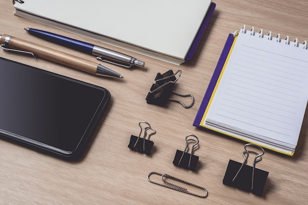 Workspace with diary or notebook and clipboard, smart phone, pen on wood