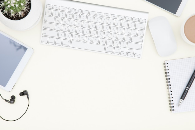 Workspace with keyboard. White office desk table with laptop, cup of coffee and supplies. Top view with copy space.