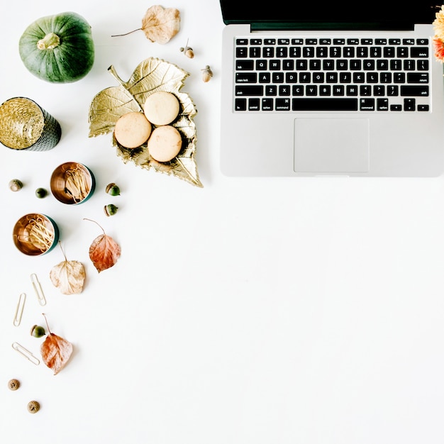 workspace with laptop, chrysanthemum bouquet, pumpkin, leaves, scissors on white