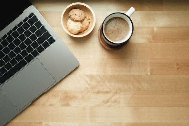 Workspace with laptop and coffee cup on wooden desk.