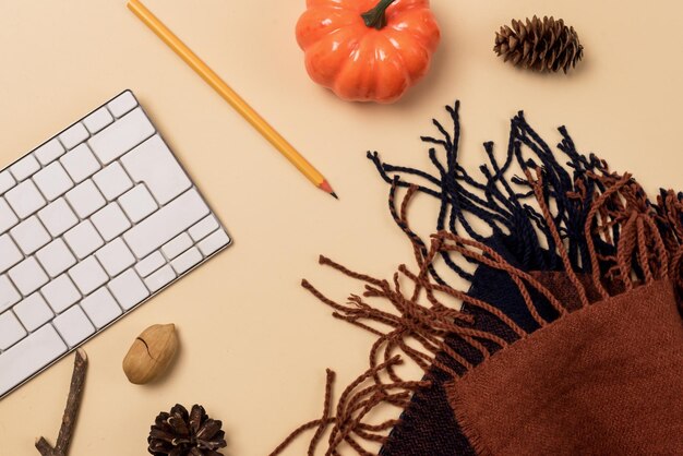 Photo workspace with laptop or keyboard pencil cozy and warm scarf pumpkin and pine cone autumn