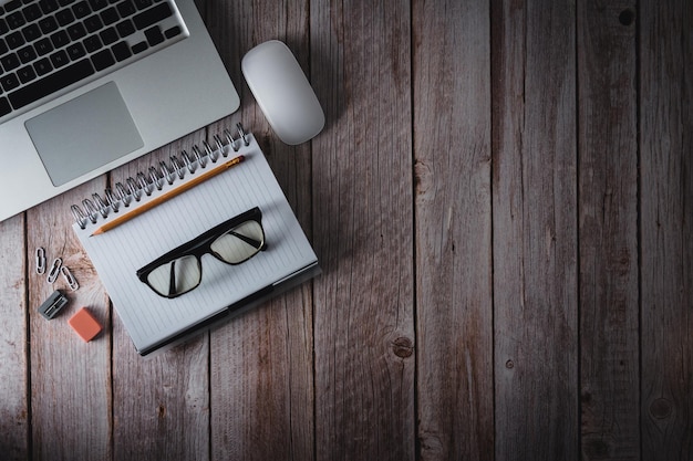 Workspace with laptop notebook and glasses on wooden background Top view Copy space Selective focus