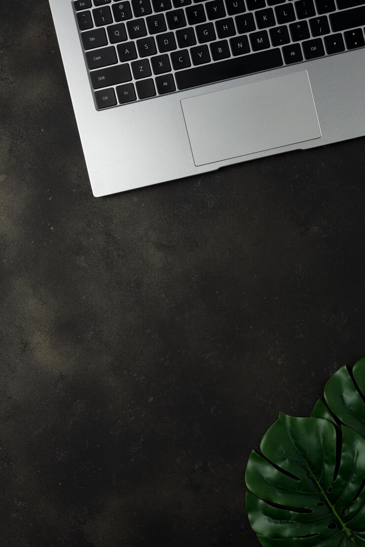 Workspace with laptop and palm leaves on black background Flat lay top view office table desk