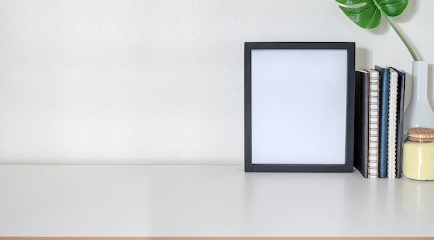 Workspace with mock up frame, office supplies and copy space on white top table and white wall.