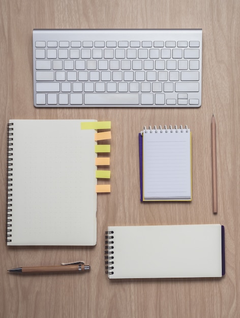 Workspace with notebooks and keyboard on wooden background