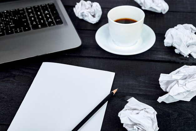 Workspace with paper, pencil, laptop and coffee cup