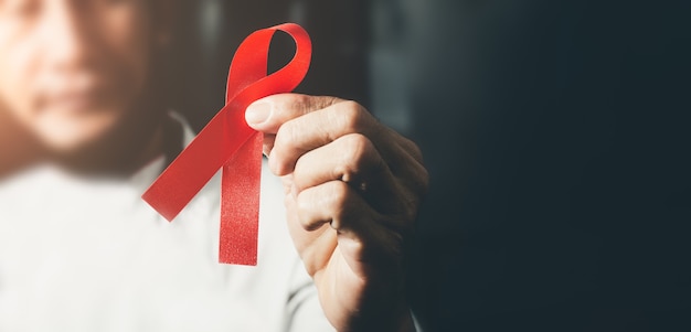 World AIDS day awareness ribbon, Female hands holding red ribbon