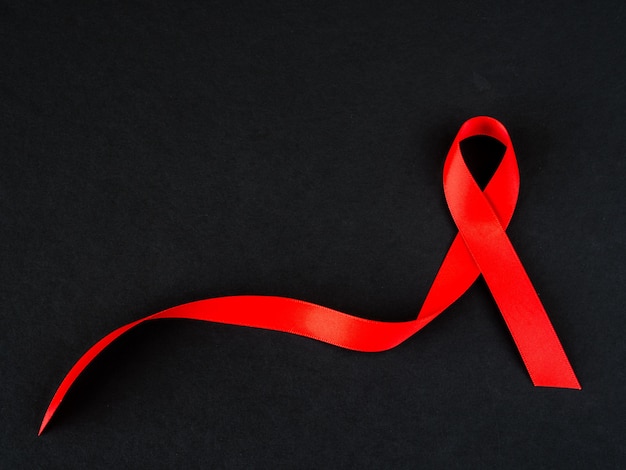 Foto concetto di giornata mondiale contro l'aids. nastro rosso su sfondo nero.