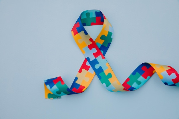 world autism awareness and pride day with puzzle pattern ribbon on blue background
