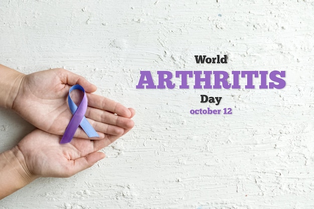 Giornata mondiale dell'artrite autoimmune mani di donna che tengono nastro viola blu su sfondo bianco