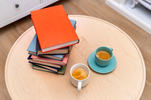 World Book Day-concept Bovenaanzicht van boeken van verschillende kleuren met twee kopjes koffie op tafel