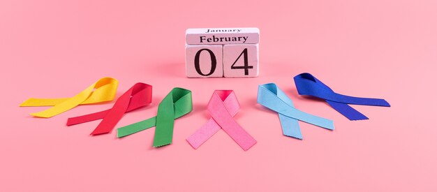 Giornata mondiale del cancro (4 febbraio). nastri colorati di consapevolezza; colore blu, rosso, verde, rosa e giallo su legno per sostenere le persone che vivono e le malattie. concetto di sanità e medicina