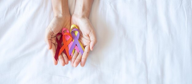 Giornata mondiale del cancro (4 febbraio). nastri colorati di consapevolezza; colore rosso, arancione, viola, rosa e giallo per sostenere le persone che vivono e le malattie. sanità e concetto medico