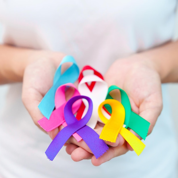 World cancer day february 4 hand holding blue red teal white pink purple and yellow ribbons for supporting people living and illness healthcare and autism awareness day concept