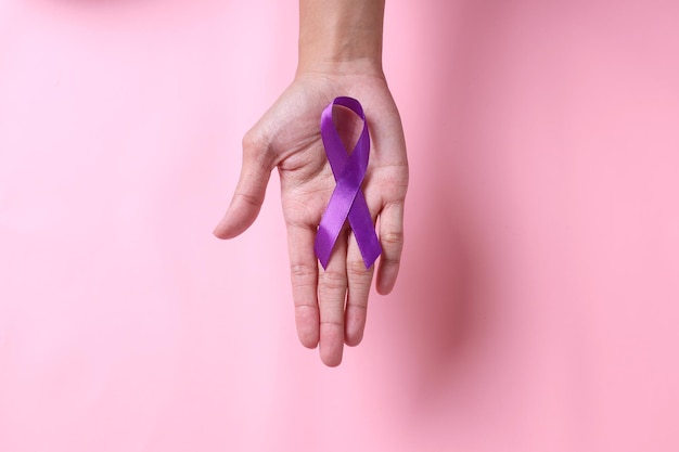 World cancer day hands holding purple ribbon on pink background World Epilepsy Awareness day