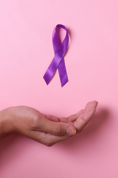 World cancer day palm hand with purple ribbon on pink background Healthcare and medical concept