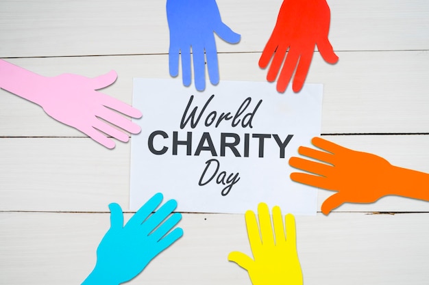 Photo world charity day text on paper with colorful hands