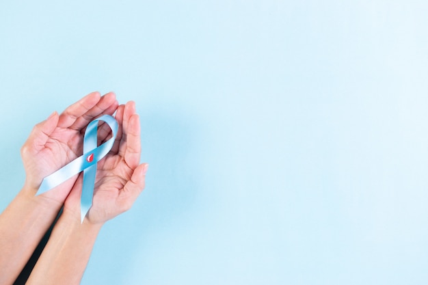 Photo world diabetes day. hand holding blue ribbon with blood drop inside