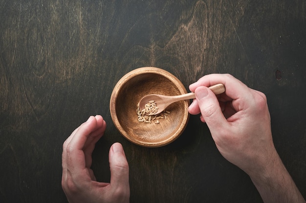 World food crisis concept Male hands take very small portion of grain food from bowl on gloomy background as symbol of global food crisis Hunger due to lack of grain Food supply crisis Top view