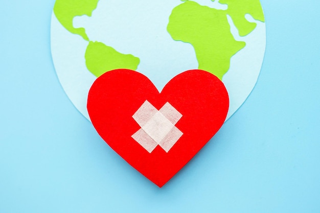 World health day concept Paper model of earth globe heart with cross on blue background