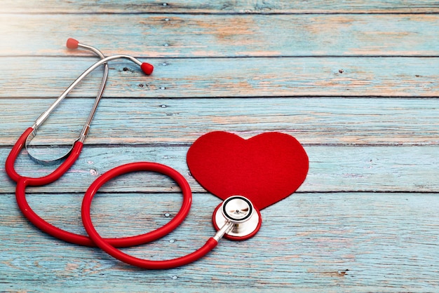 世界保健デー、ヘルスケアと医療の概念、赤い聴診器と青い木製の背景に赤いハート