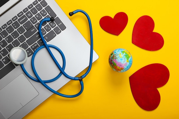 Foto giornata mondiale della salute. laptop e stetoscopio con cuore, globo giallo