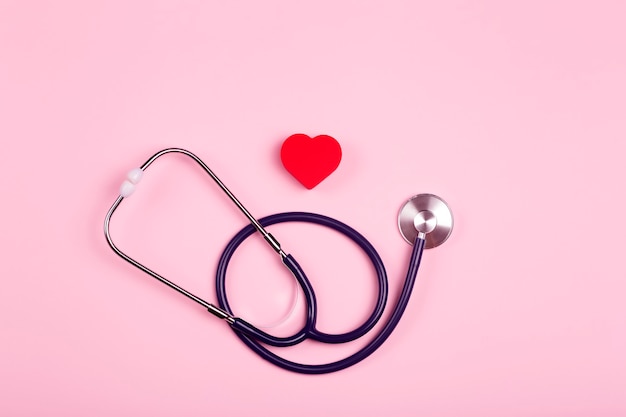 Sfondo di giornata mondiale del cuore. cuore come simbolo di salute, cura, carità, donazione e cardiologia su uno sfondo rosa con uno statoscopio medico.