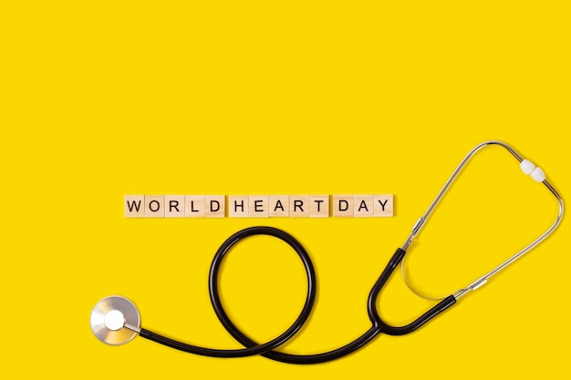 World heart day text with stethoscope on yellow