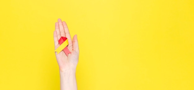 World Hepatitis Day concept. Woman holds awareness symbol red-yellow ribbon