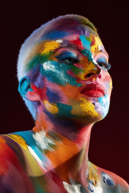 The world is my canvas and I create my reality Studio shot of a young woman posing with multicoloured paint on her face