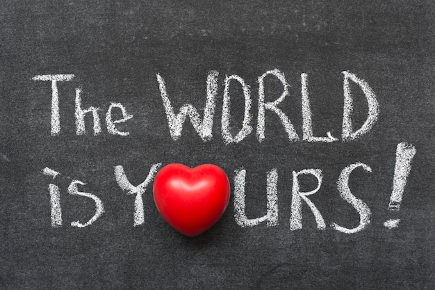 the world is yours exclamation handwritten on blackboard with heart symbol instead of O