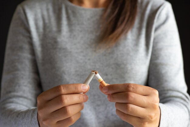 Foto giornata mondiale senza tabacco, chiuda sulla mano della donna che rompe le sigarette