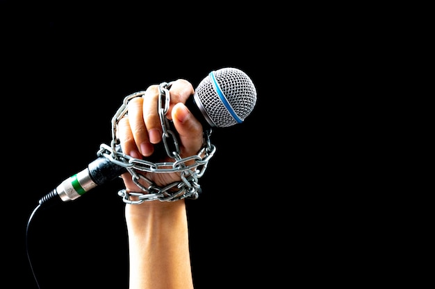 World press freedom day concept. Woman hand with microphone tied with a chain