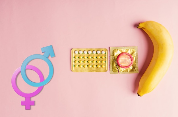 Foto preservativo per la salute sessuale mondiale sulla pillola contraccettiva di banana e segno di genere maschile femminile