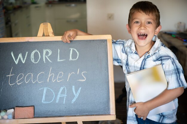 World Teacher's Day greeting, pupil boy near the chalkboard, chalk inscription text