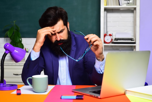 World teachers day back to school learning and education tired male teacher in auditorium bearded