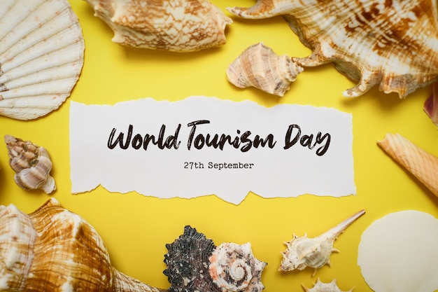 World Tourism Day incription over yellow background, with palm leaves, clam shell, and shoes flat lay background