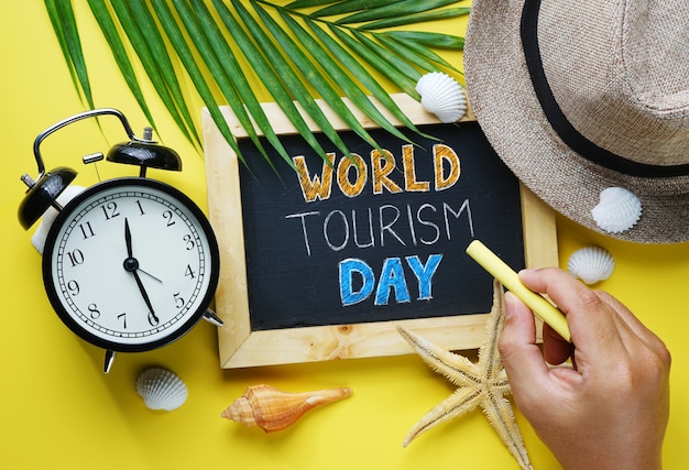 Photo world tourism day typography. hand holding yellow chalk and blackboard