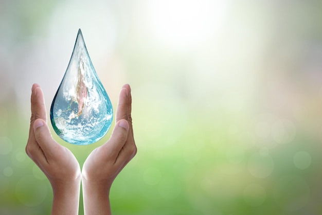 Giornata mondiale dell'acqua mani in attesa del mondo a forma di goccia d'acqua su sfondo sfocato fiori e cielo con la luce del sole elementi di questa immagine fornita dalla nasa