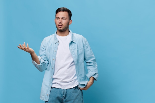 Worried about problem tanned handsome man in casual basic\
tshirt hold hand up look aside posing isolated on blue studio\
background copy space banner mockup people emotions lifestyle\
concept