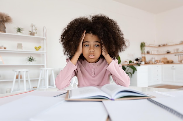 Worried african american school girl doing homework