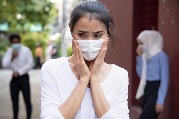 사진 대유행으로 인해 공공 장소에서 다른 사람들과 거리를 유지하는 사회적 거리의 새로운 정상적인 생활 방식에 대한 두려움으로 얼굴 마스크를 쓴 걱정스럽고 겁 먹은 아시아 여성