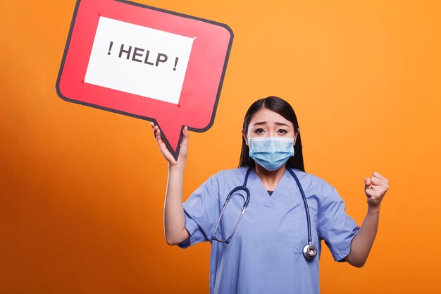 Worried asian hospital worker holding cardboard speech bubble sign