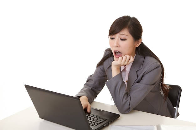 Worried business woman of Asian using laptop on desk, closeup portrait.