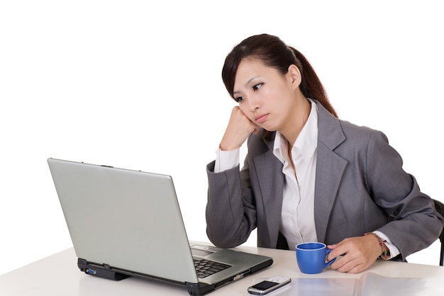 Worried business woman working with laptop on desk against white background.