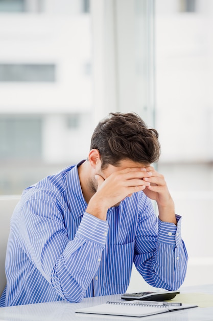 Worried businessman calculating accounts on a calculator