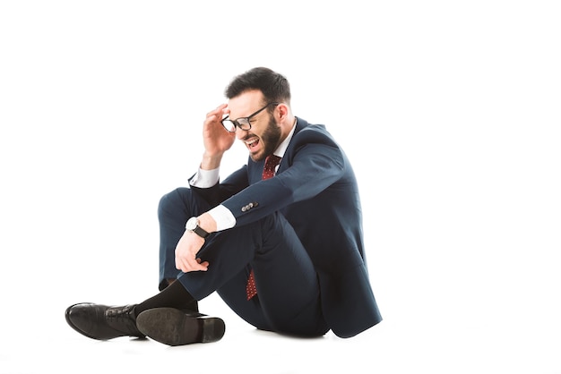 Worried businessman holding hand near head while sitting on white background