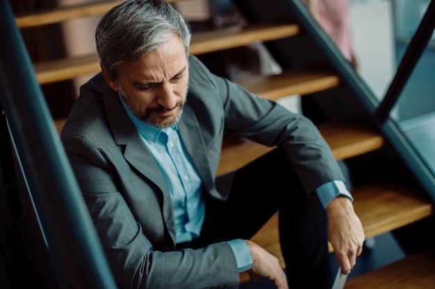 Worried businessman sitting on staircase and thinking of\
something