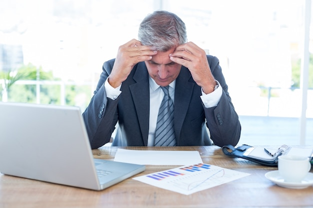 Worried businessman with head in hands 